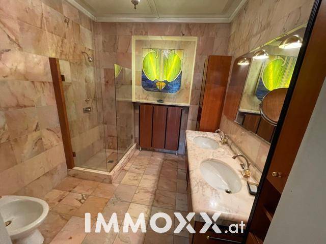 Geräumiges Badezimmer mit Marmorfliesen, Doppelwaschbecken und Duschkabine.