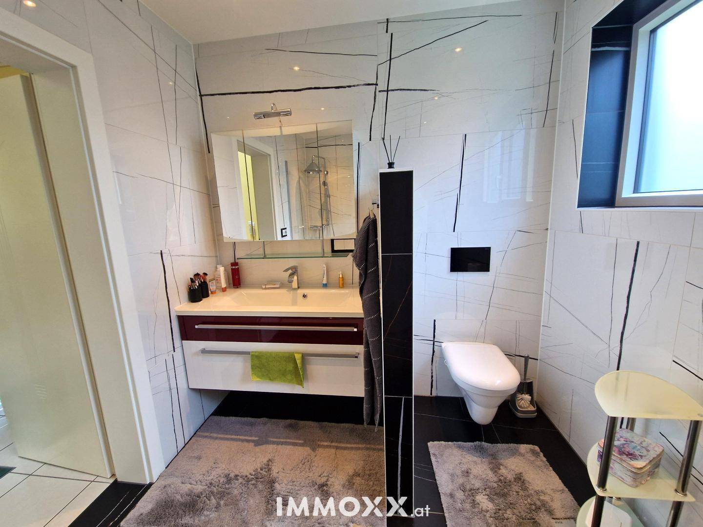 Modernes Badezimmer mit Waschtisch, Spiegelschrank und wandhängendem WC.