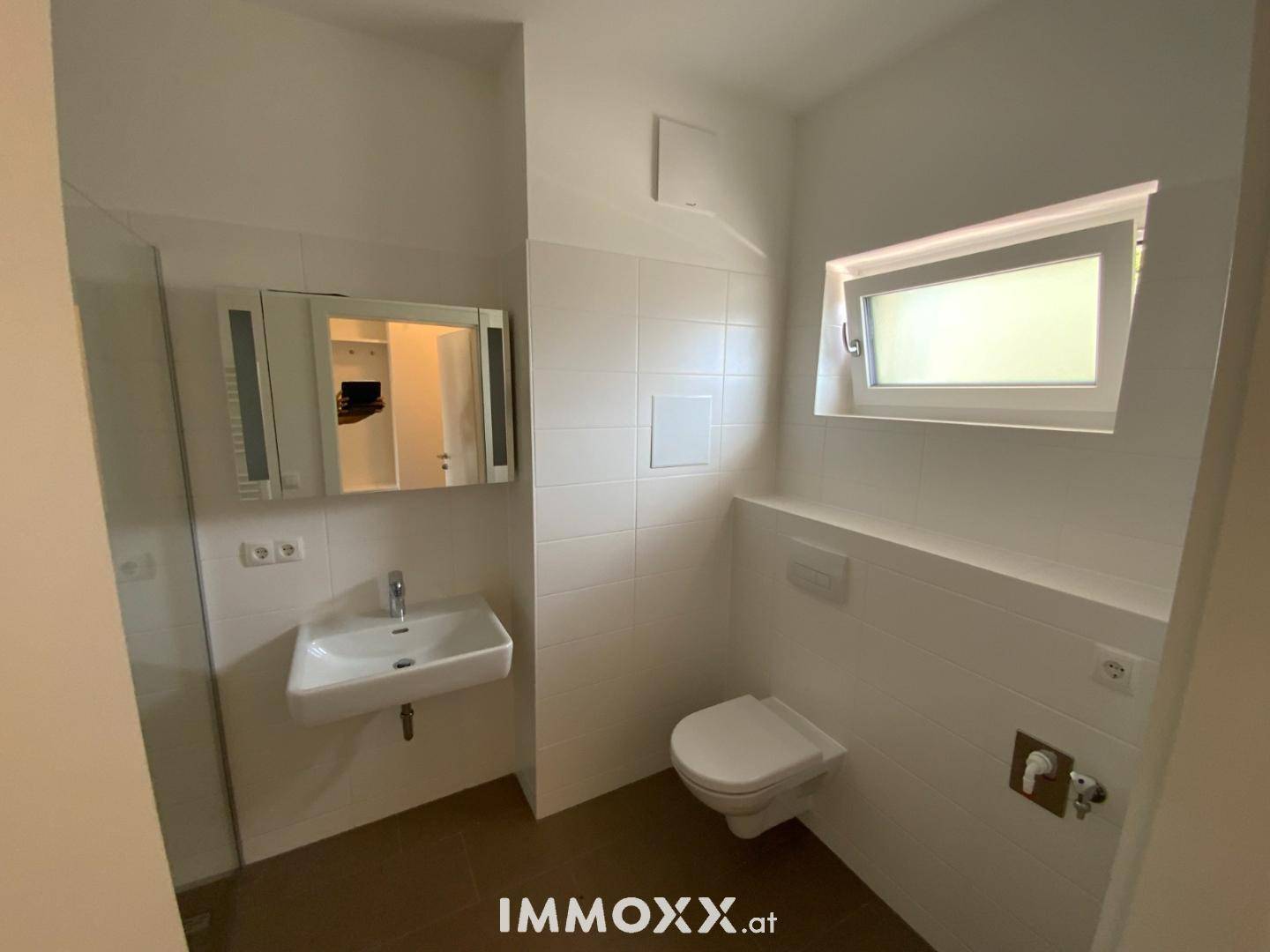 Helles Gäste-WC mit wandhängender Toilette, Waschbecken und Fenster.