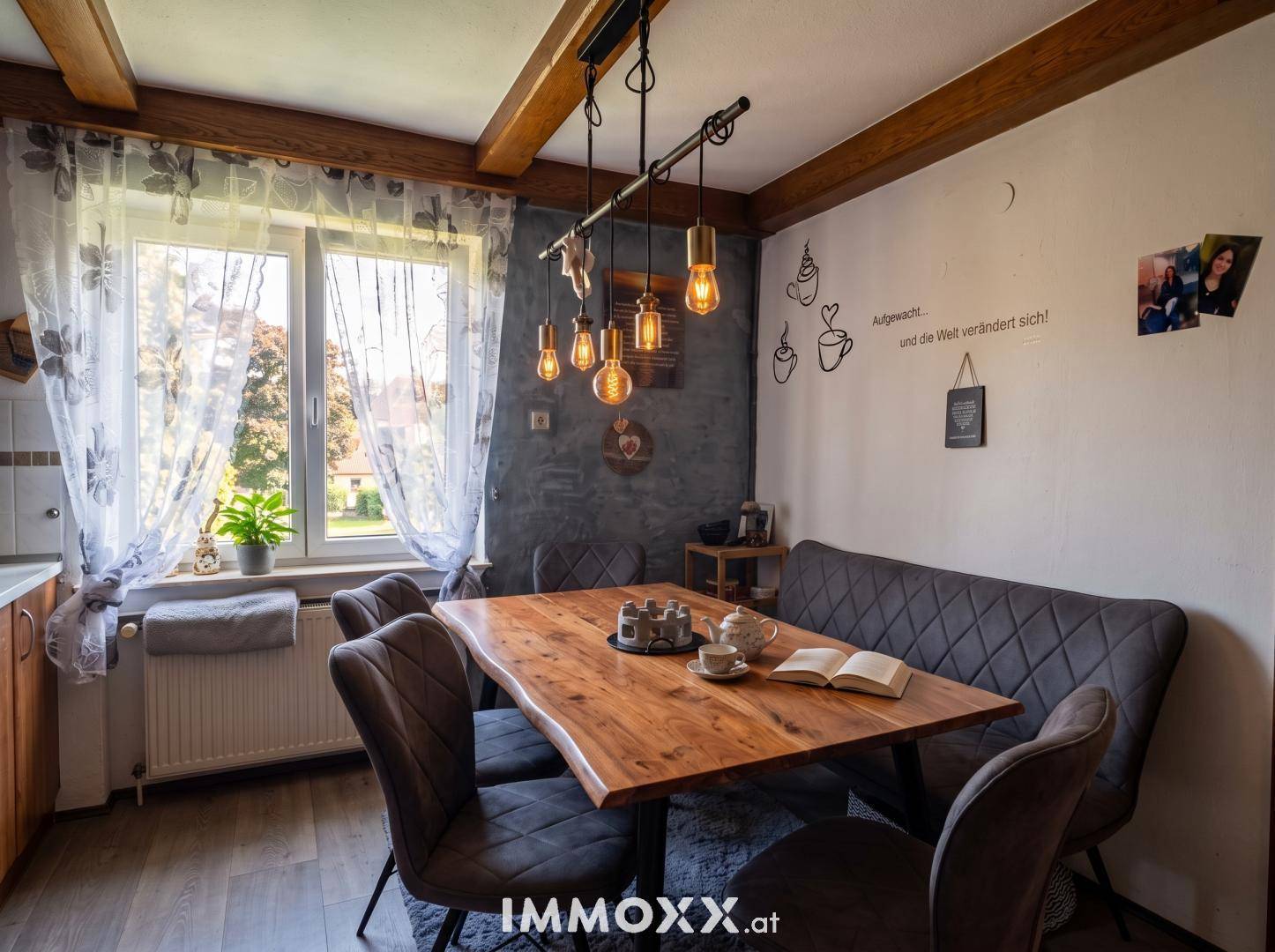 Gemütlicher Essbereich mit Holztisch, gepolsterter Bank und rustikalen Deckenbalken.