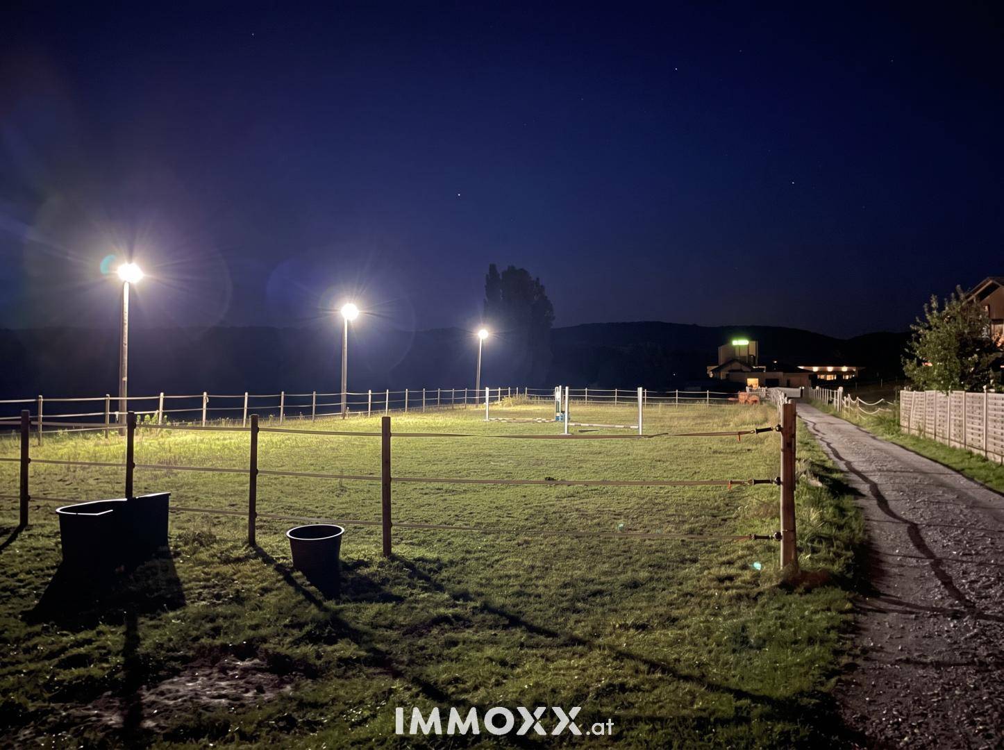 Beleuchteter Reitplatz oder Paddock in der Nacht mit klarem Sternenhimmel.