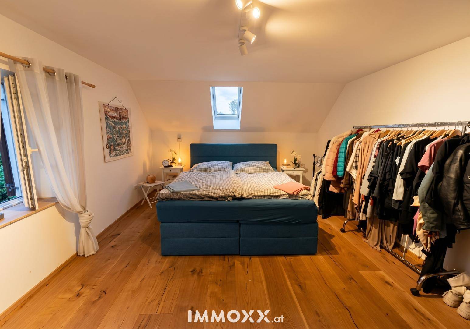 Schlafzimmer im Dachgeschoss mit Holzboden, Dachfenster und Kleiderstange.