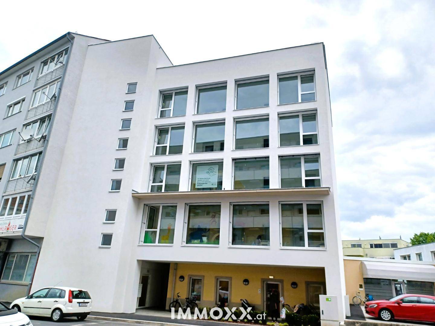 Ansicht der modernen Gebäudefassade mit großen Fenstern und einer klaren architektonischen Linie.