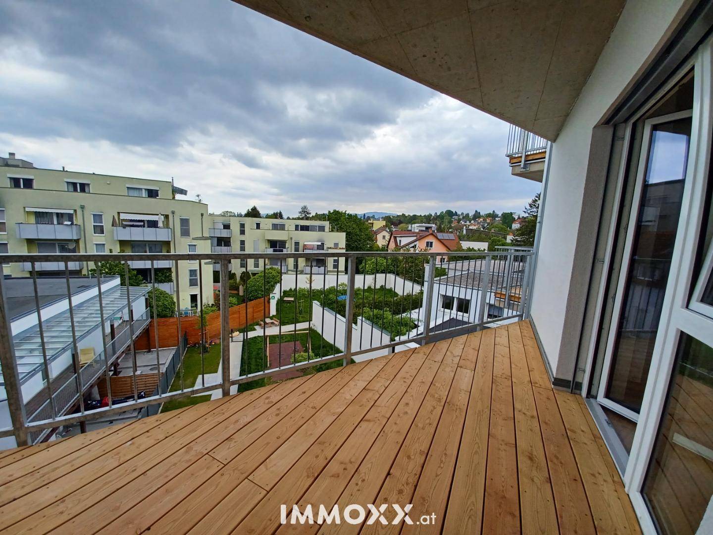 Geräumiger Balkon mit Holzboden und weitem Blick über die umliegende Wohngegend.