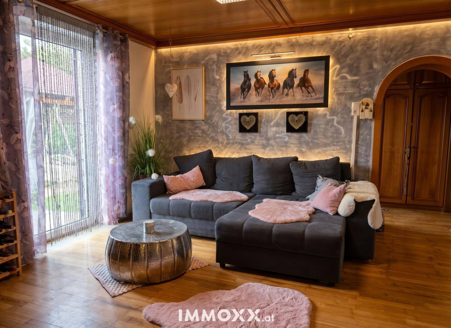 Modernes Wohnzimmer mit großem Sofa, Holzboden und indirekter Beleuchtung.