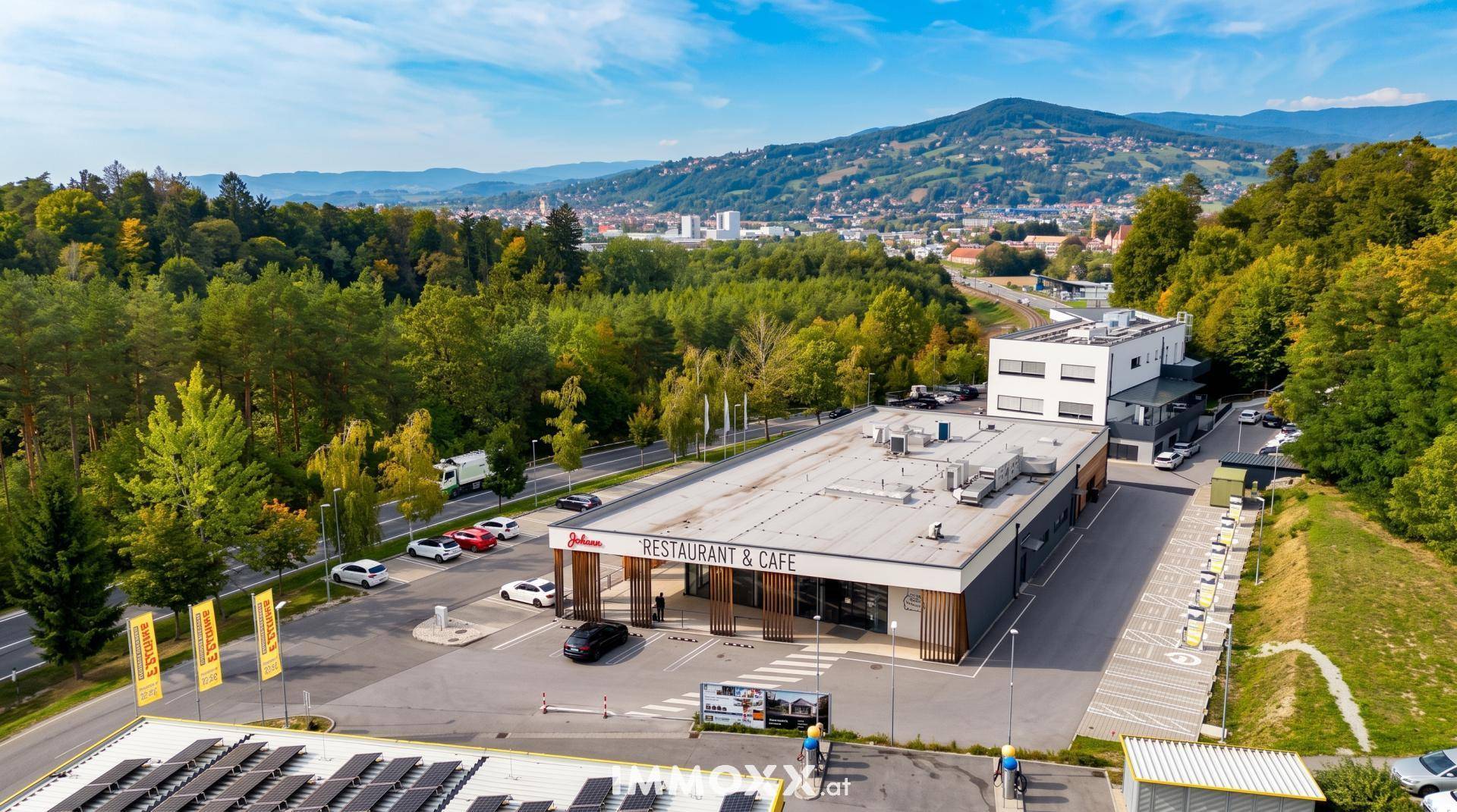 Luftaufnahme eines Gewerbekomplexes mit Restaurant, Tankstelle und Solaranlagen auf den Dächern.