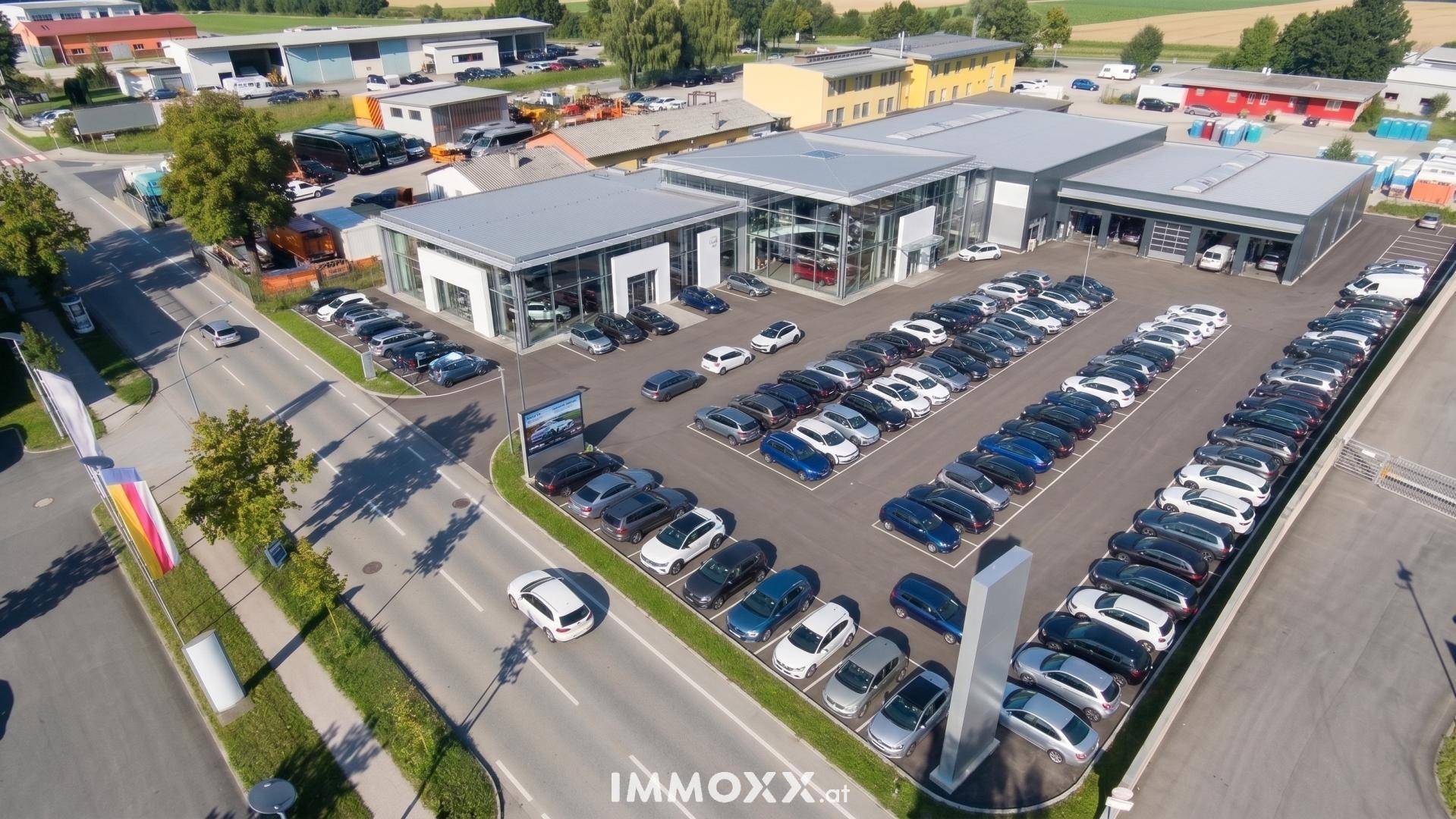 Luftaufnahme eines modernen Autohauses mit Glasfassaden, mehreren Gebäuden und einem großen Parkplatz.