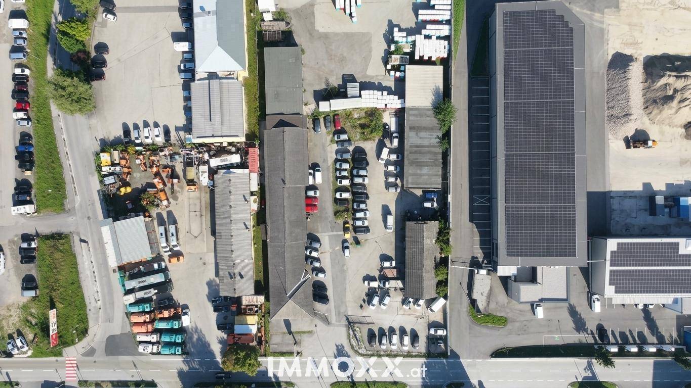 Draufsicht aus der Vogelperspektive auf ein Gewerbegebiet mit Gebäuden, Parkplätzen und Solaranlagen auf einem Dach.