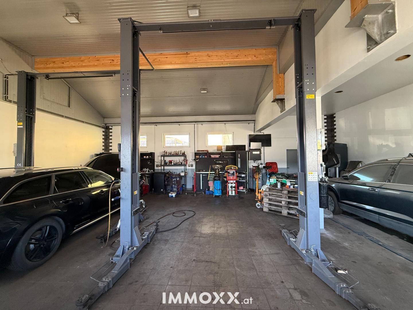 Werkstatt oder Garage mit zwei Hebebühnen für Fahrzeuge und Werkzeugen im Hintergrund.