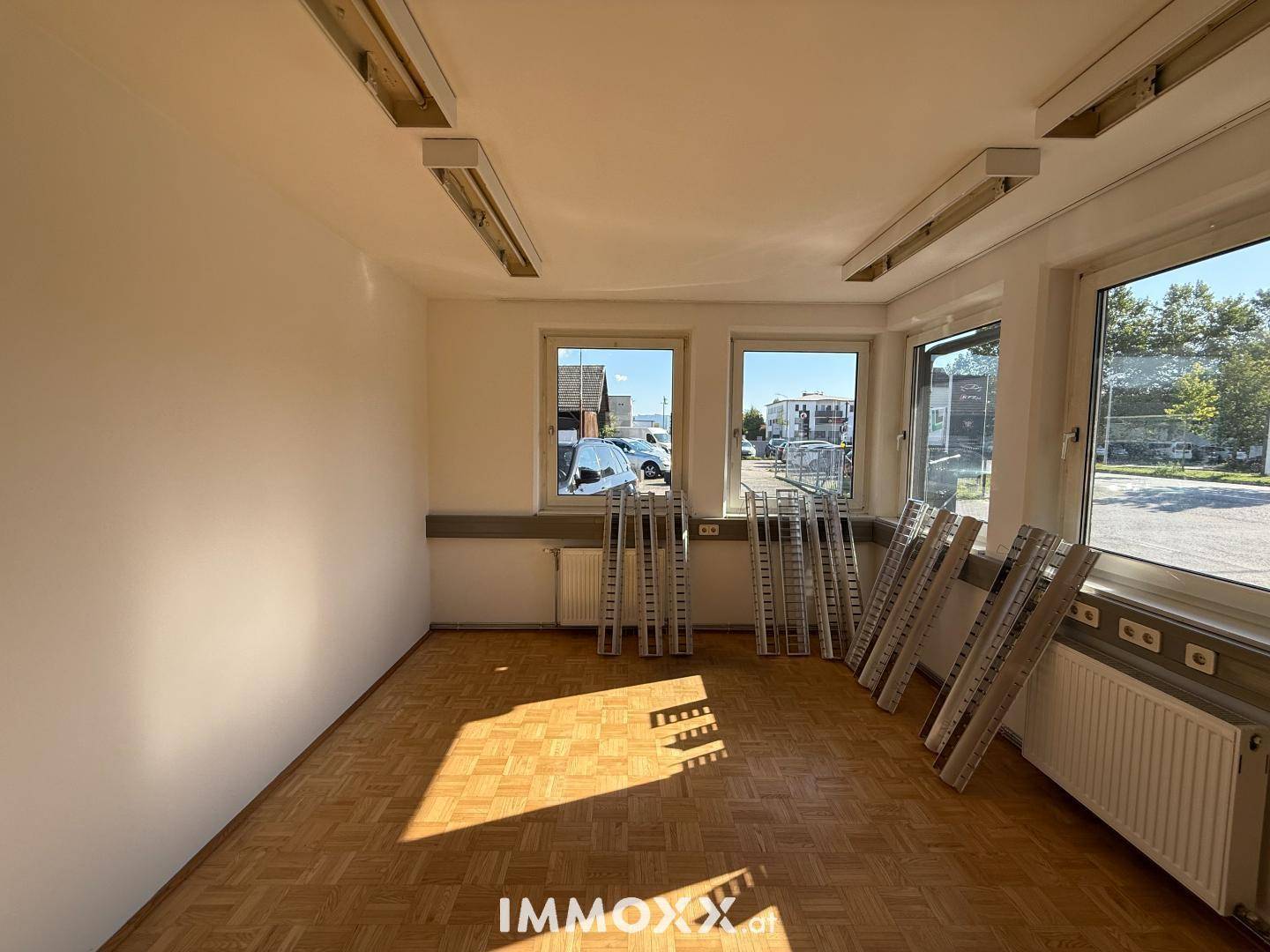 Heller, leerer Raum mit Parkettboden, weißen Wänden und mehreren Fenstern, ideal als Büro oder Verkaufsfläche.