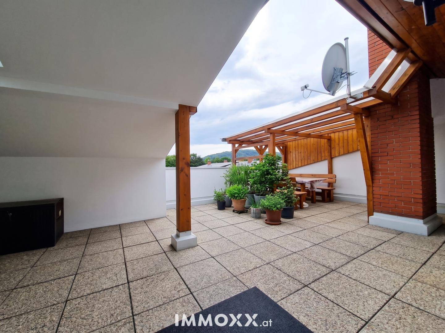 Geräumige Dachterrasse mit Fliesenboden, Holzpergola und Pflanzen, ideal für entspannte Stunden im Freien.