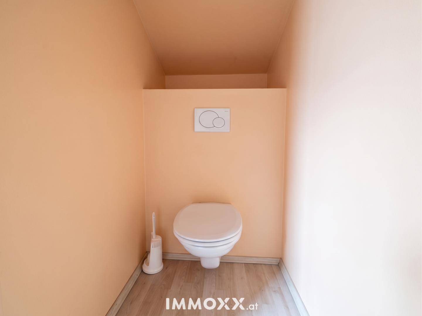 Kleines WC mit pfirsichfarbenen Wänden, modernem Wand-WC und Laminatboden.