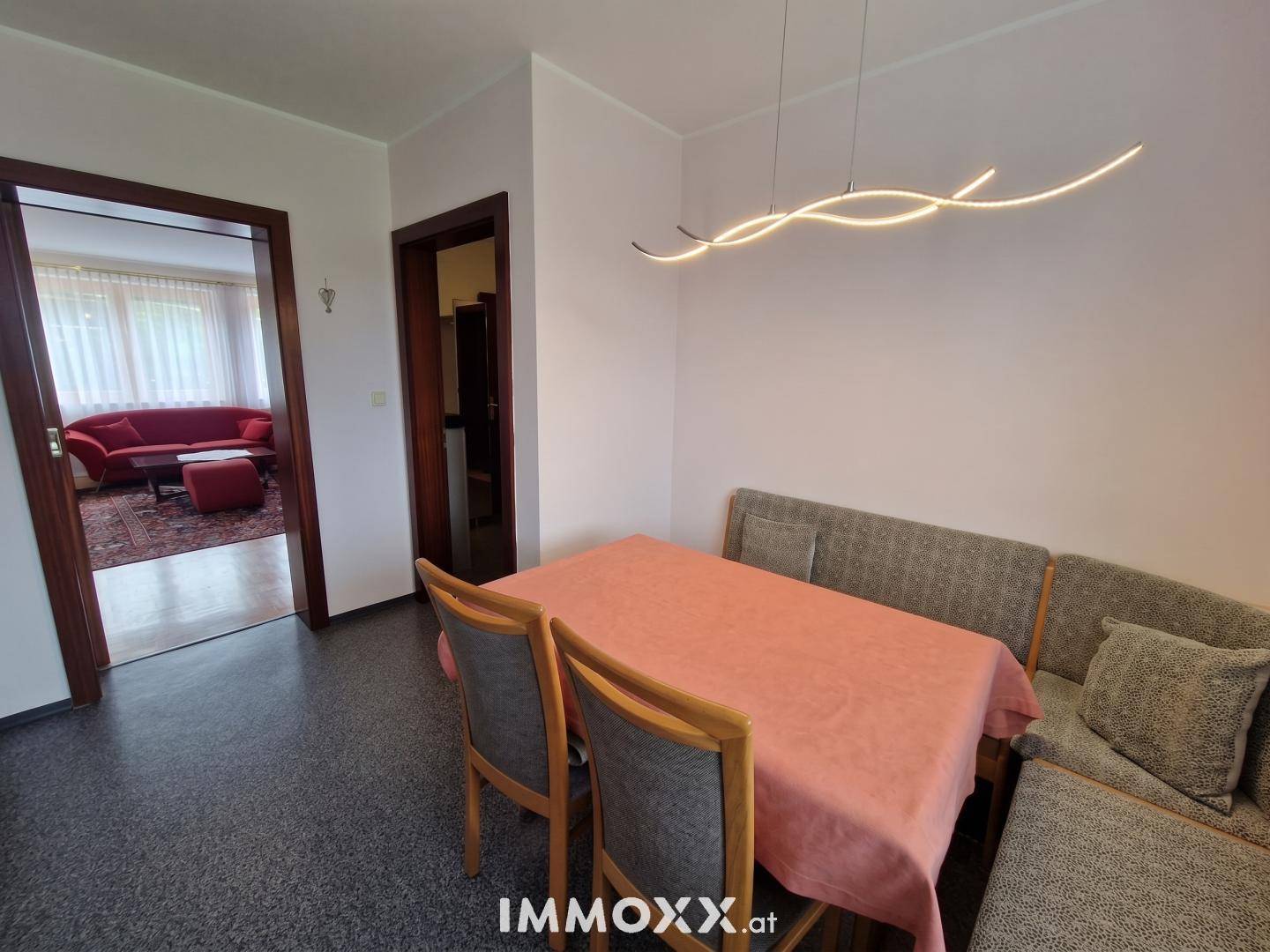 Heller Essbereich mit modernem Lichtdesign und Zugang zu einem angrenzenden Wohnzimmer.