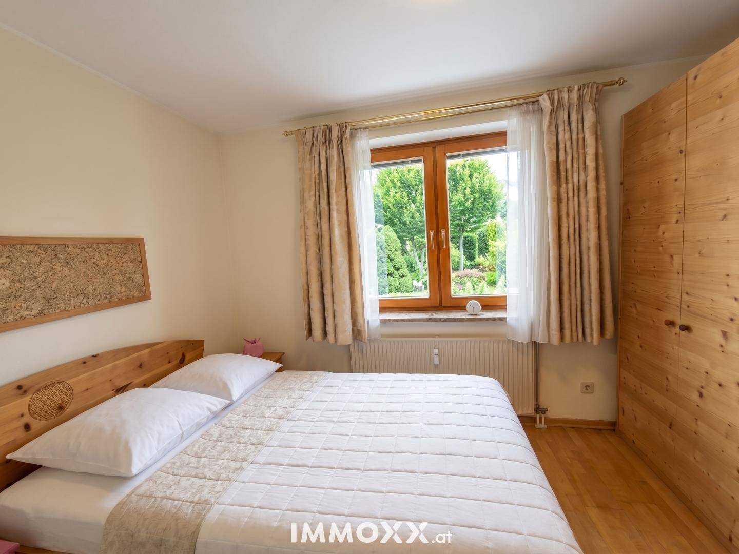 Gemütliches Schlafzimmer mit Holzbett, passendem Kleiderschrank und Blick auf den grünen Garten.