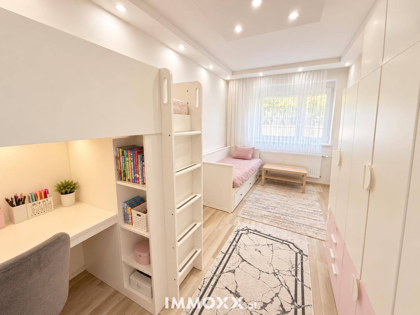 Helles Kinderzimmer mit Etagenbett, Schreibtisch und farbigen Kleiderschränken.