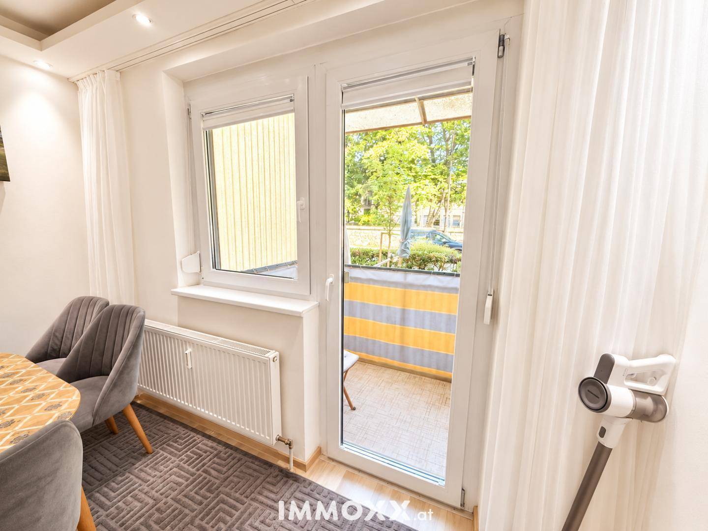 Zugang zum Balkon von einem hellen Raum aus mit Blick ins Grüne.