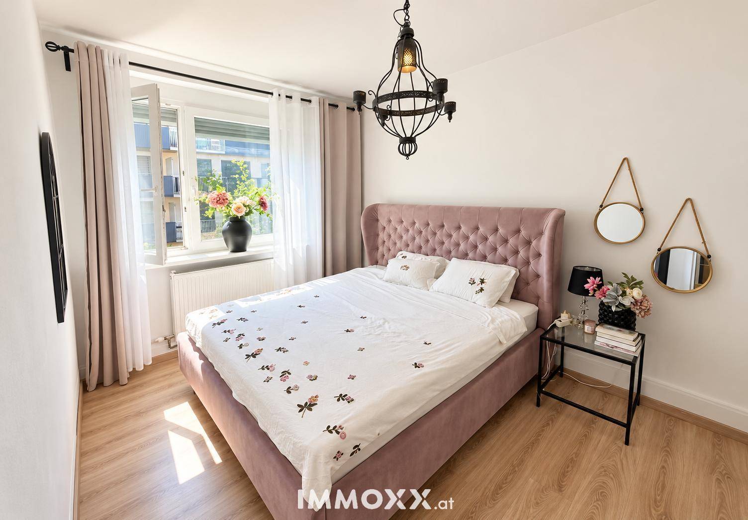 Gemütliches Schlafzimmer mit gepolstertem Bett, Laminatboden und Fenster.