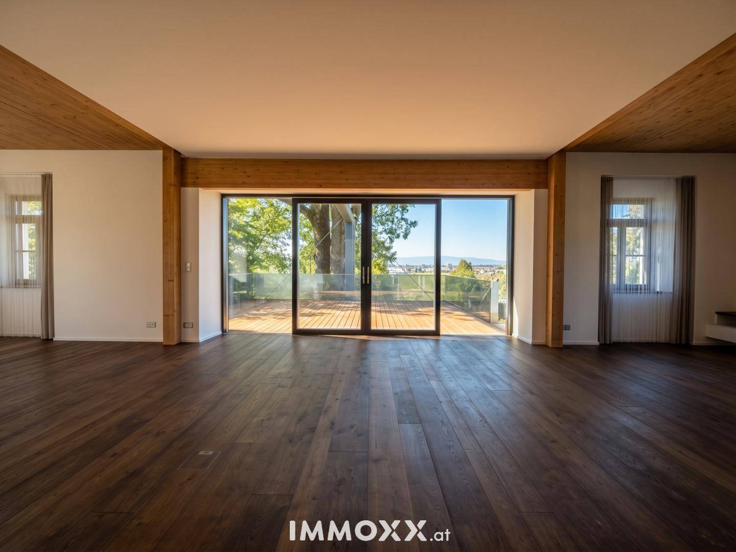 Heller Wohnraum mit Holzbalken, großen Schiebetüren zur Terrasse und Holzboden.