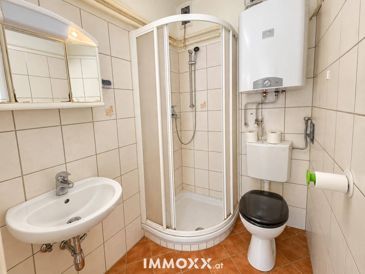Funktionales Badezimmer mit Duschkabine, WC, Waschbecken und Fliesenboden.