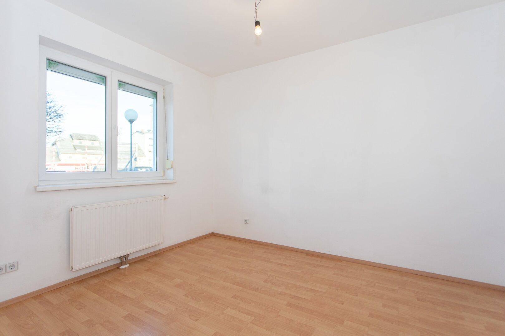 Geräumiges Schlafzimmer mit großem Fenster und Heizkörper, ideal für individuelle Einrichtungsideen.