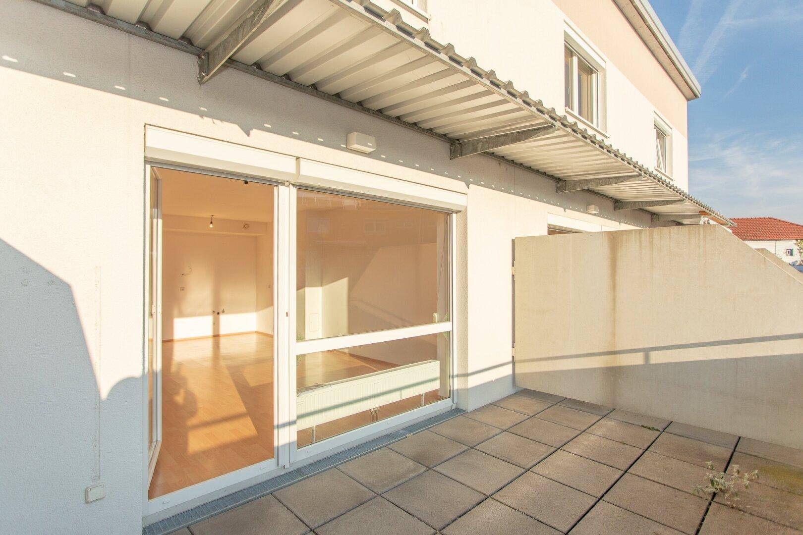 Sonniger Terrassenbereich mit Fliesenboden und Blick auf die umliegenden Gebäude, ideal für Entspannung.