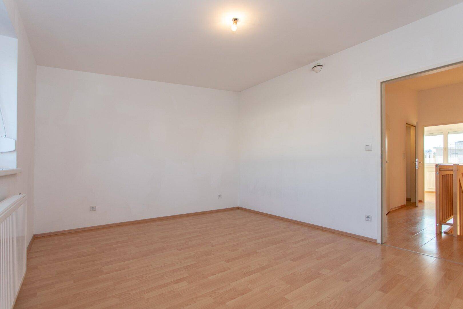 Leeres Schlafzimmer mit Laminatboden und weiß gestrichenen Wänden, bietet viel Gestaltungspotenzial.