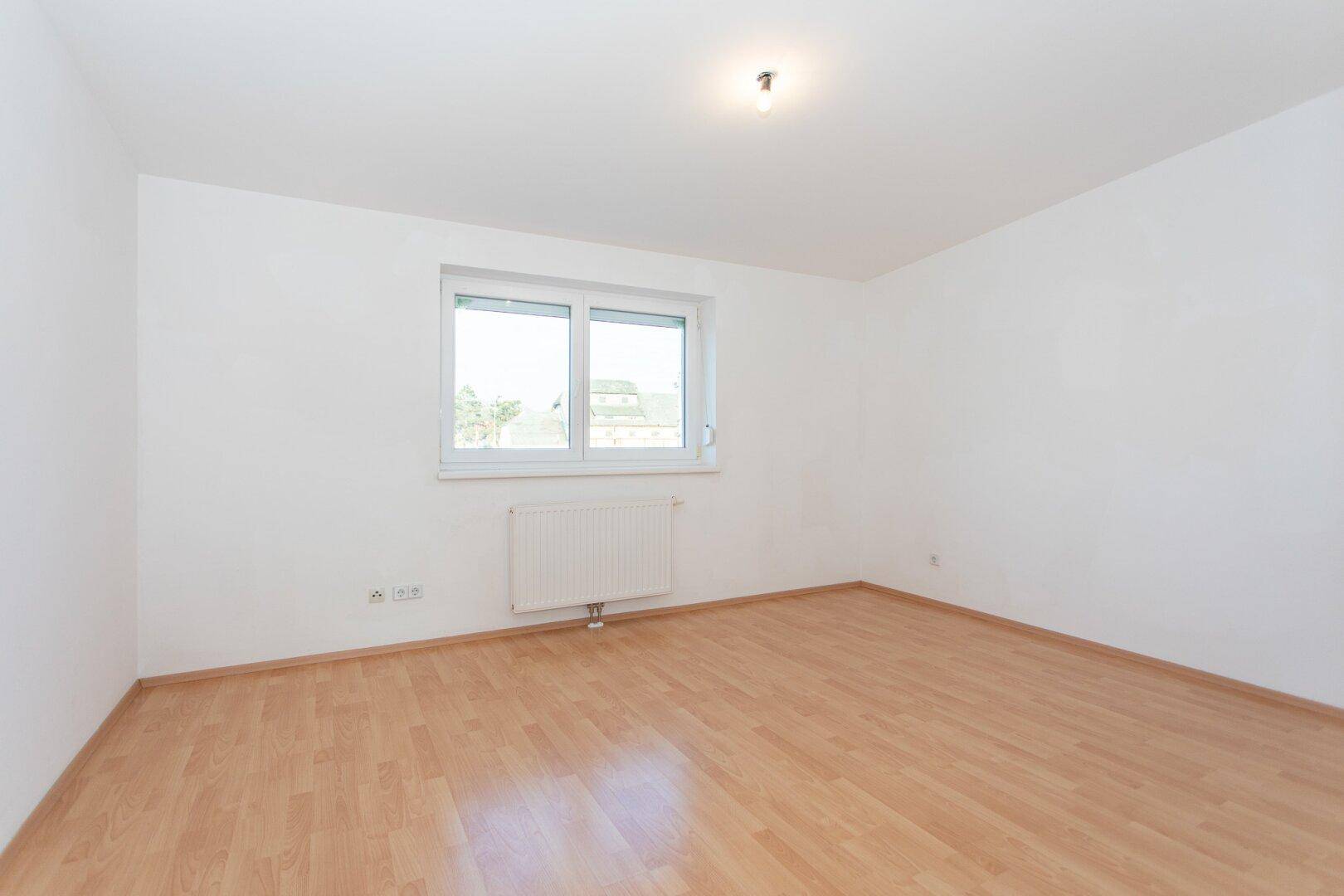 Helles Schlafzimmer mit Fenster und Heizkörper, ideal für eine gemütliche Einrichtung.