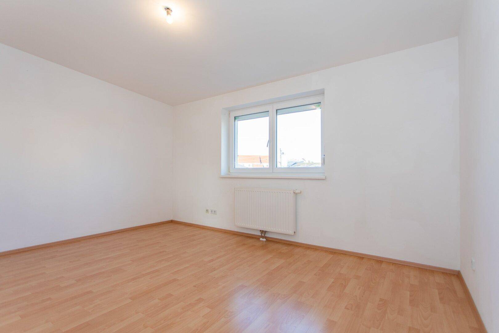 Helles Schlafzimmer mit Laminatboden und Fenster, ideal für ein ruhiges und komfortables Wohnen.