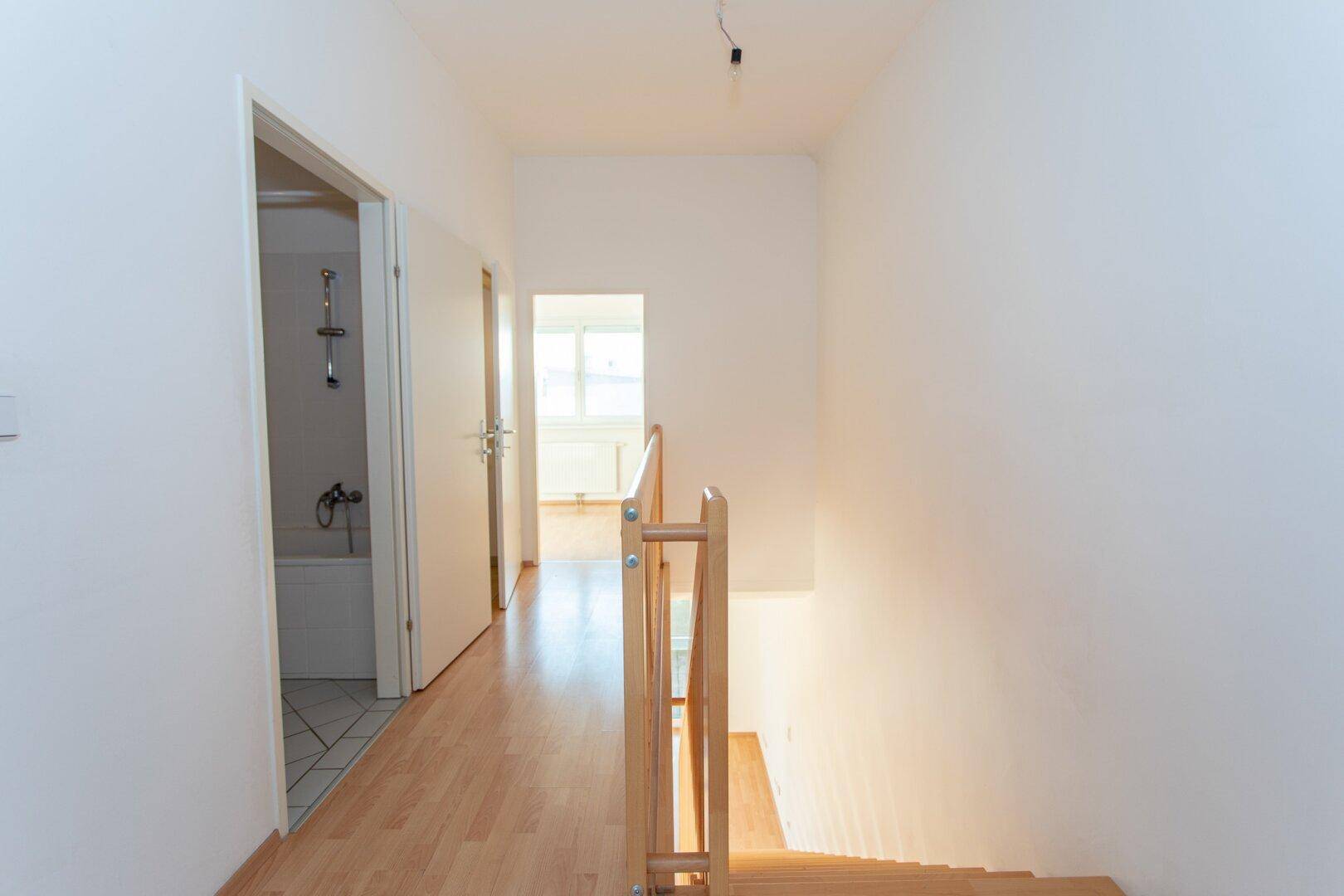 Heller Flur im Obergeschoss mit Laminatboden, der zu Badezimmer und weiteren Zimmern führt.