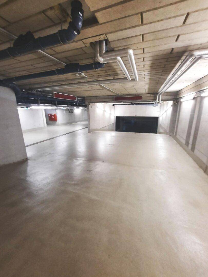 Zufahrtsrampe zu einem weiteren Bereich der Tiefgarage mit sichtbaren Installationen.