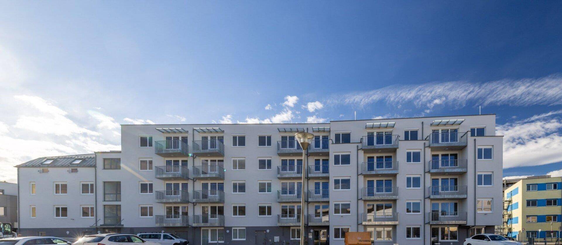 Moderne Wohnanlage mit vielen Balkonen unter blauem Himmel, bietet attraktiven Wohnraum.