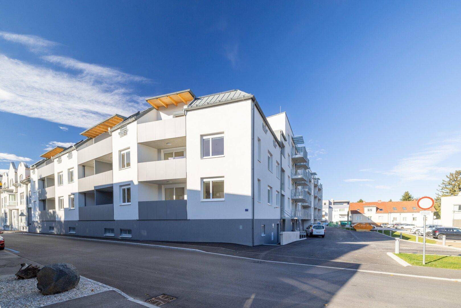 Eckansicht eines modernen Wohngebäudes mit Balkonen und heller Fassade, ansprechende Architektur.