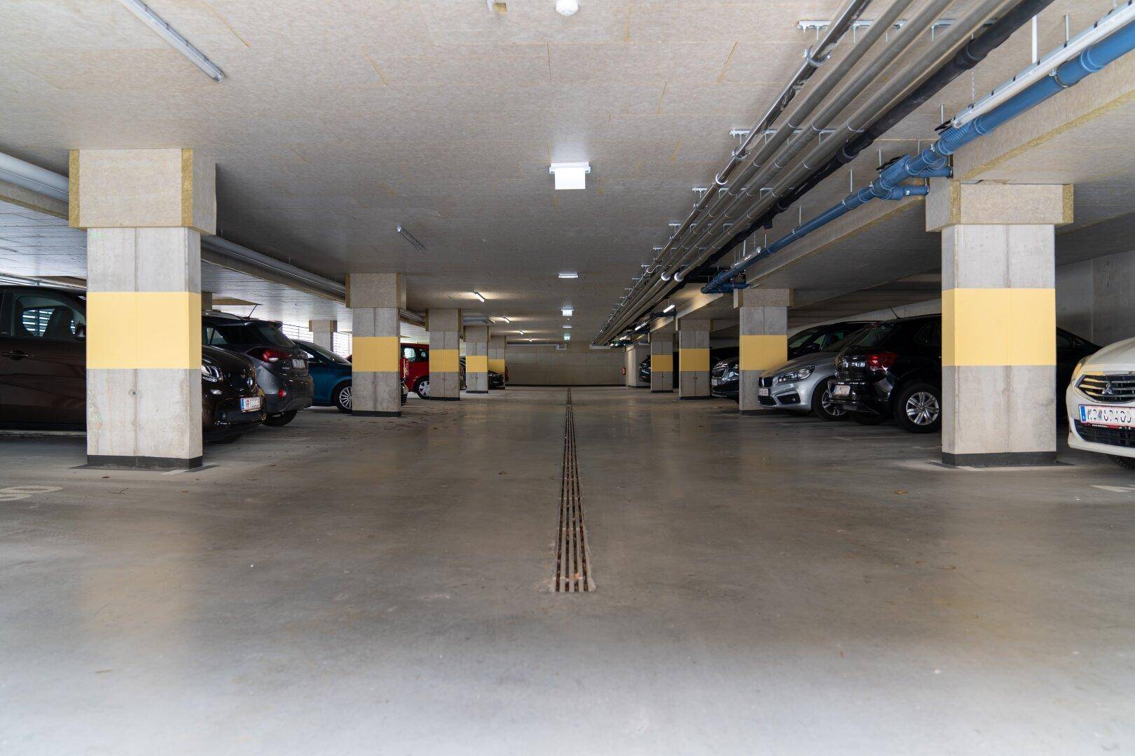 Geräumige Tiefgarage mit Betonpfeilern und ausreichend Stellplätzen für Bewohner.