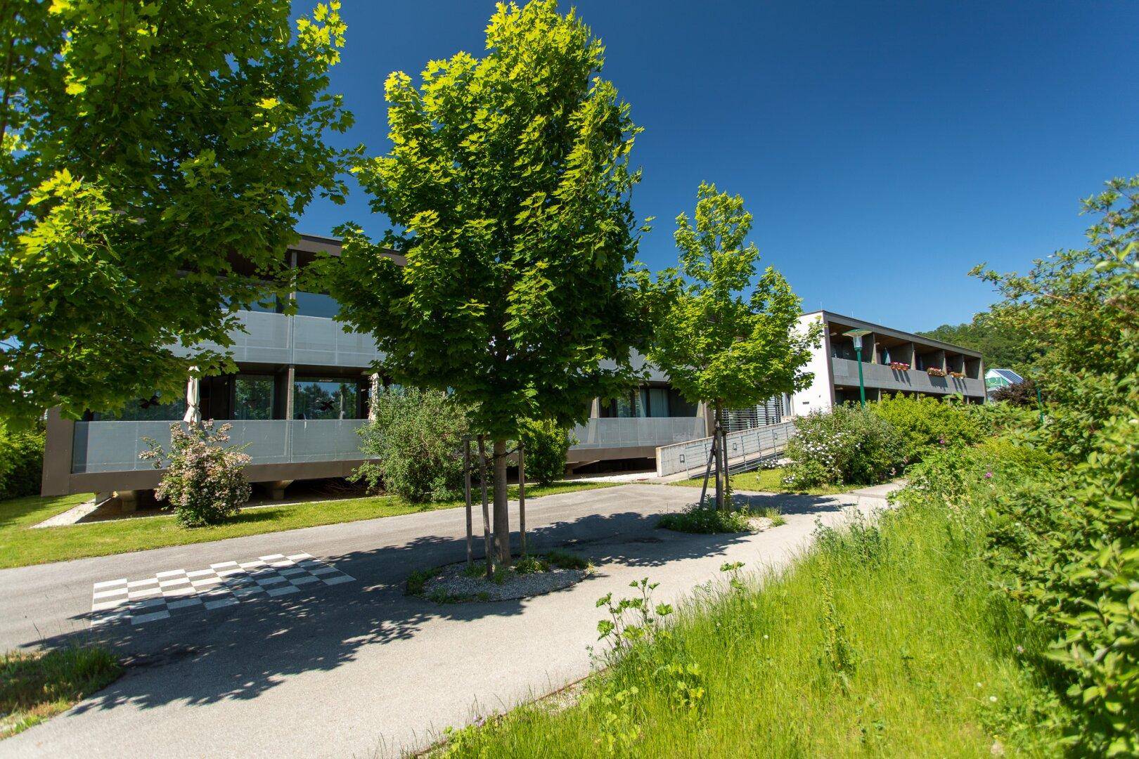 Wohnanlage mit moderner Architektur, umgeben von Bäumen und Grünflächen.