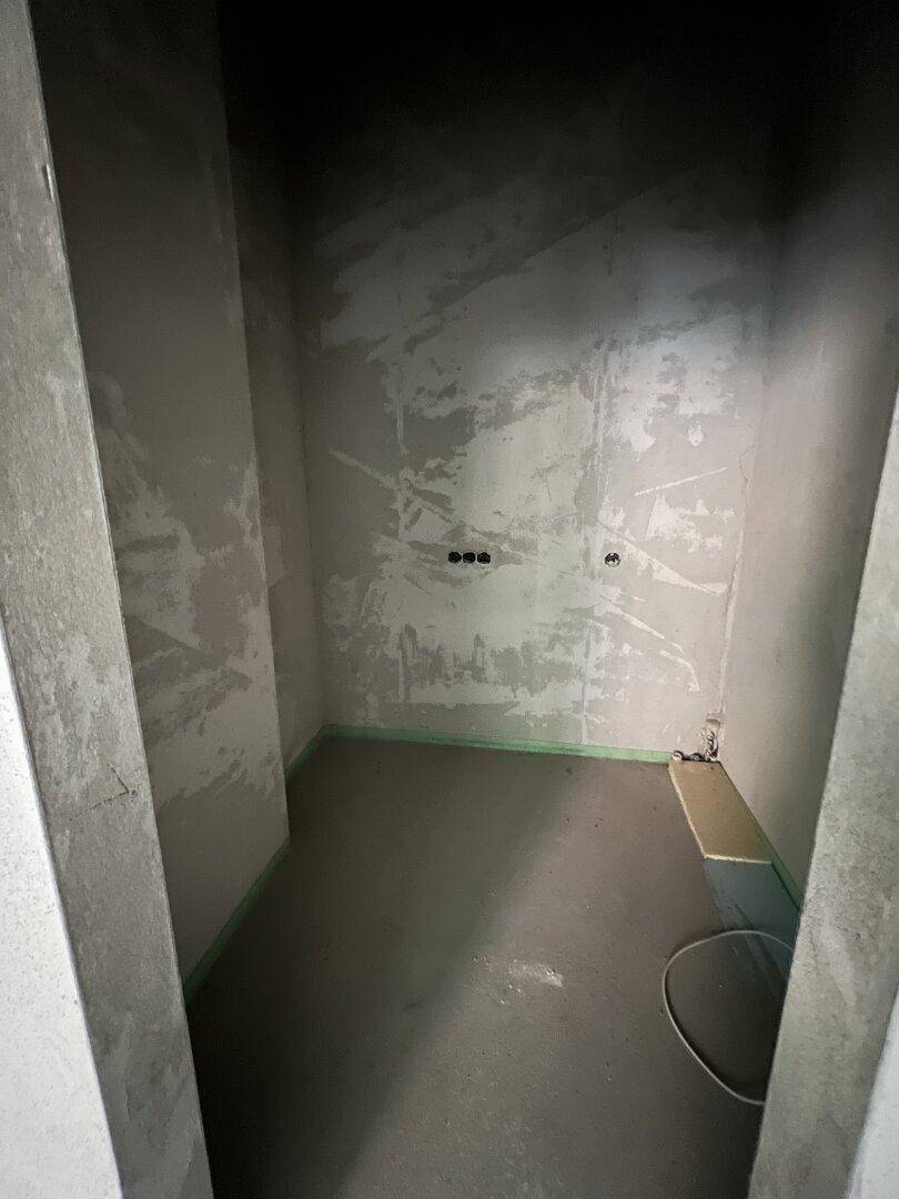 Kleiner Raum im Rohbau mit vorbereiteten Anschlüssen für Sanitärinstallationen.
