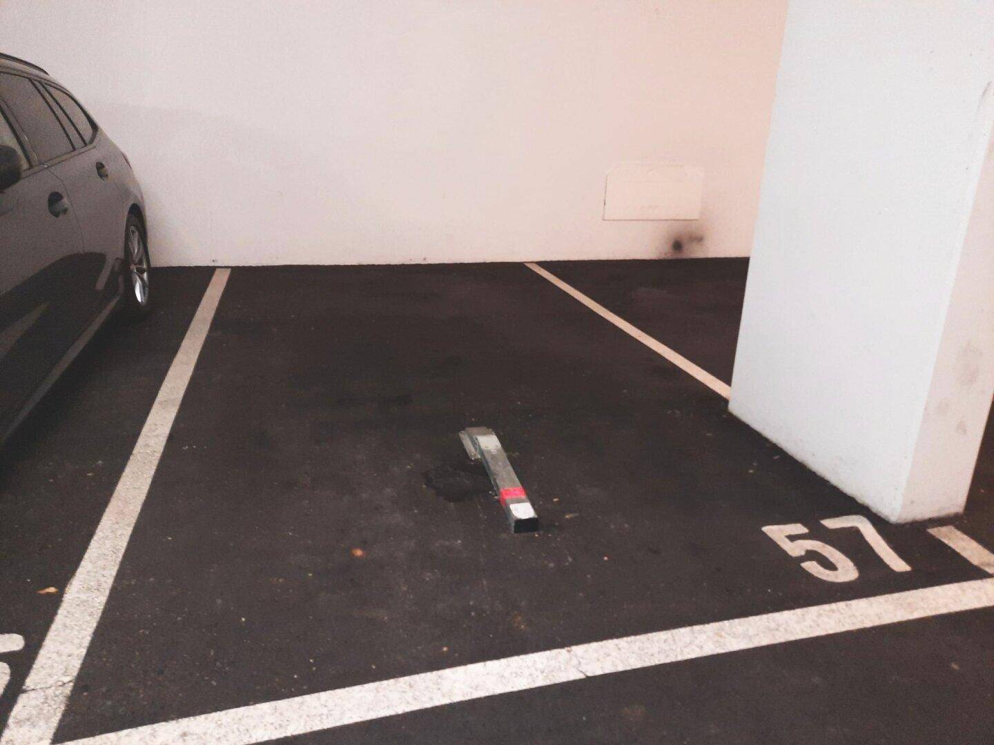 Tiefgaragenstellplatz Nummer 57 mit einem geparkten Auto und einer mechanischen Parkplatzsperre für Sicherheit.