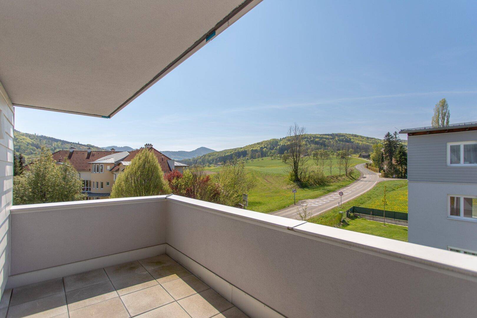 Balkon mit Fliesenboden und weitem Blick über grüne Hügel und die umliegende Landschaft.