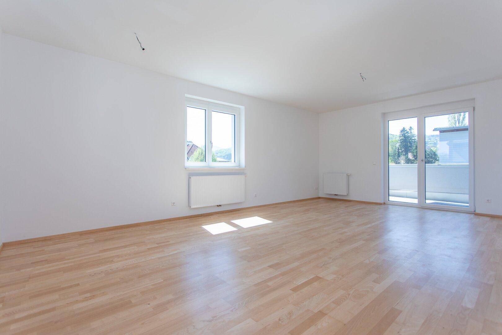 Geräumiges, helles Zimmer mit Holzparkett, großen Fenstern und direktem Balkonzugang.