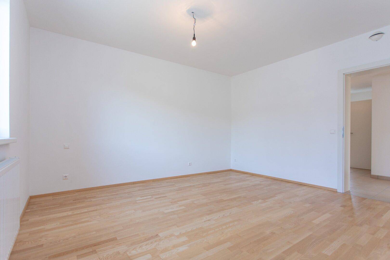 Helles Zimmer mit Parkettboden und weiß gestrichenen Wänden, bietet eine neutrale Basis.