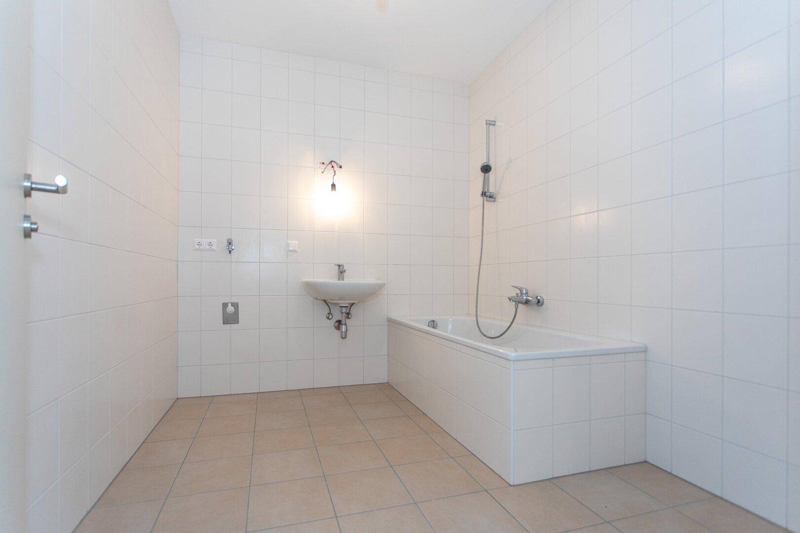 Modernes Badezimmer mit weißen Fliesen, Badewanne und Waschbecken, in sehr gutem Zustand.