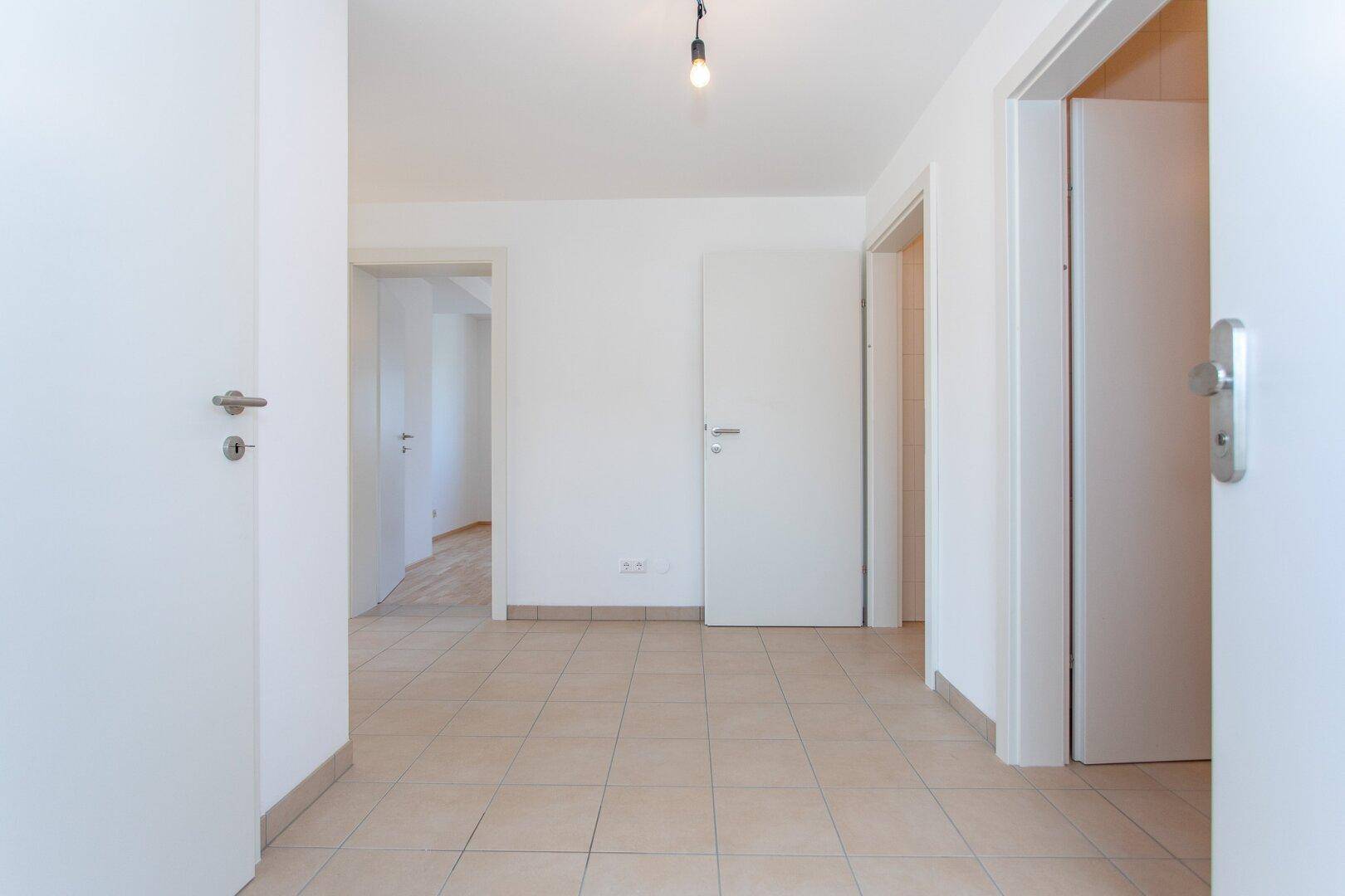 Geräumiger Flur mit hellen Fliesen und mehreren Türen, die zu verschiedenen Räumen führen.