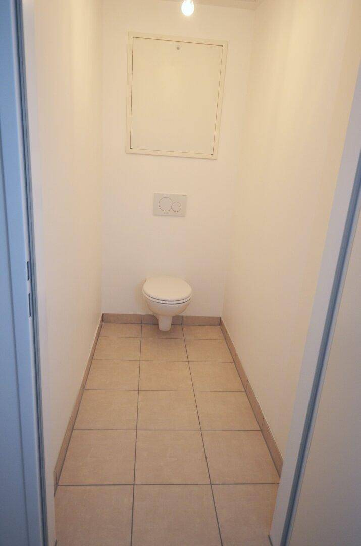 Kleines, separates WC mit Wand-WC und hellen Fliesen, funktional und sauber.