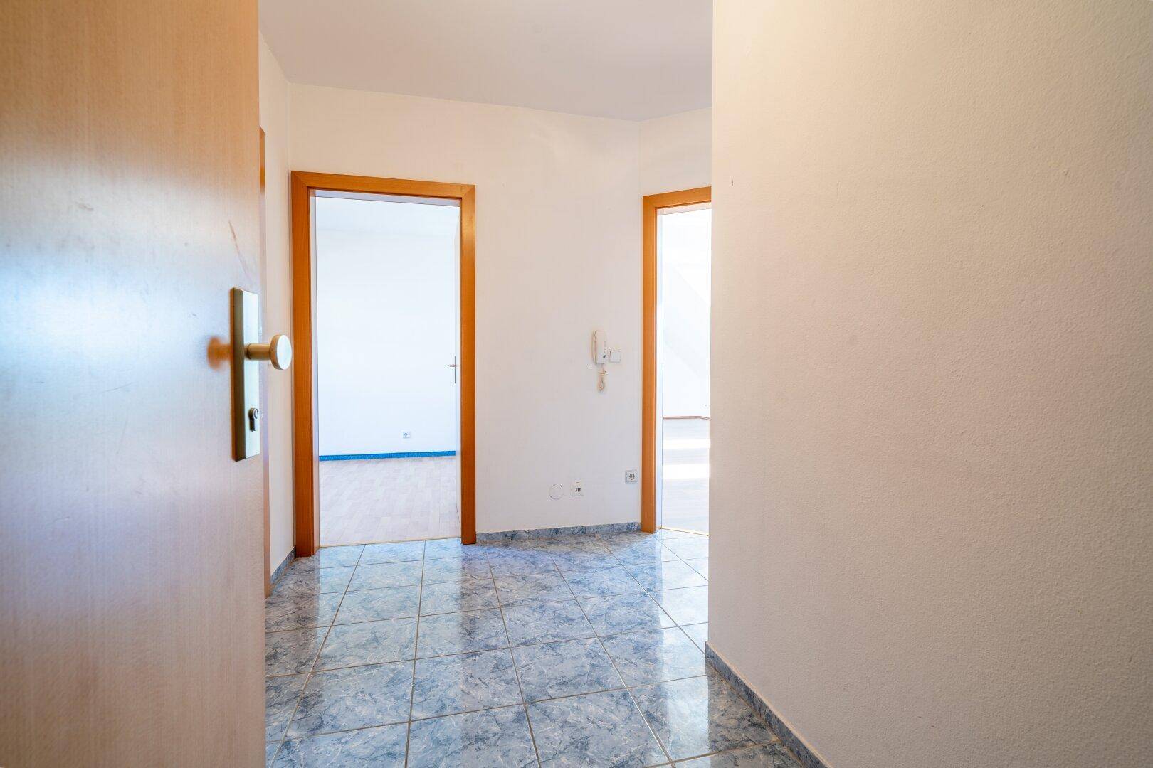 Flur mit gemustertem Fliesenboden und mehreren Holztüren, die zu verschiedenen Räumen führen.