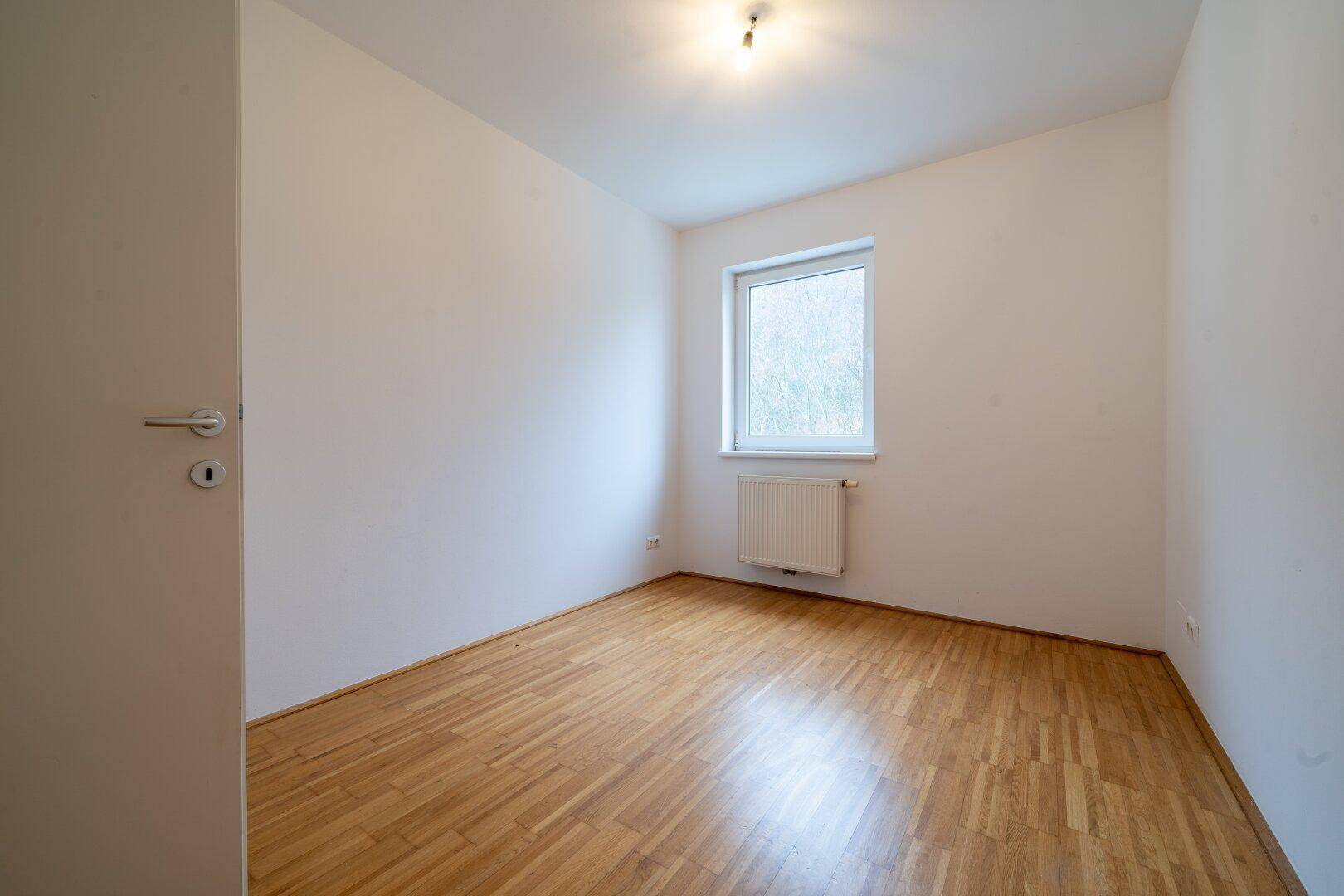 Ruhiges Zimmer mit Parkettboden und einem Fenster, ideal als Schlaf- oder Arbeitszimmer.