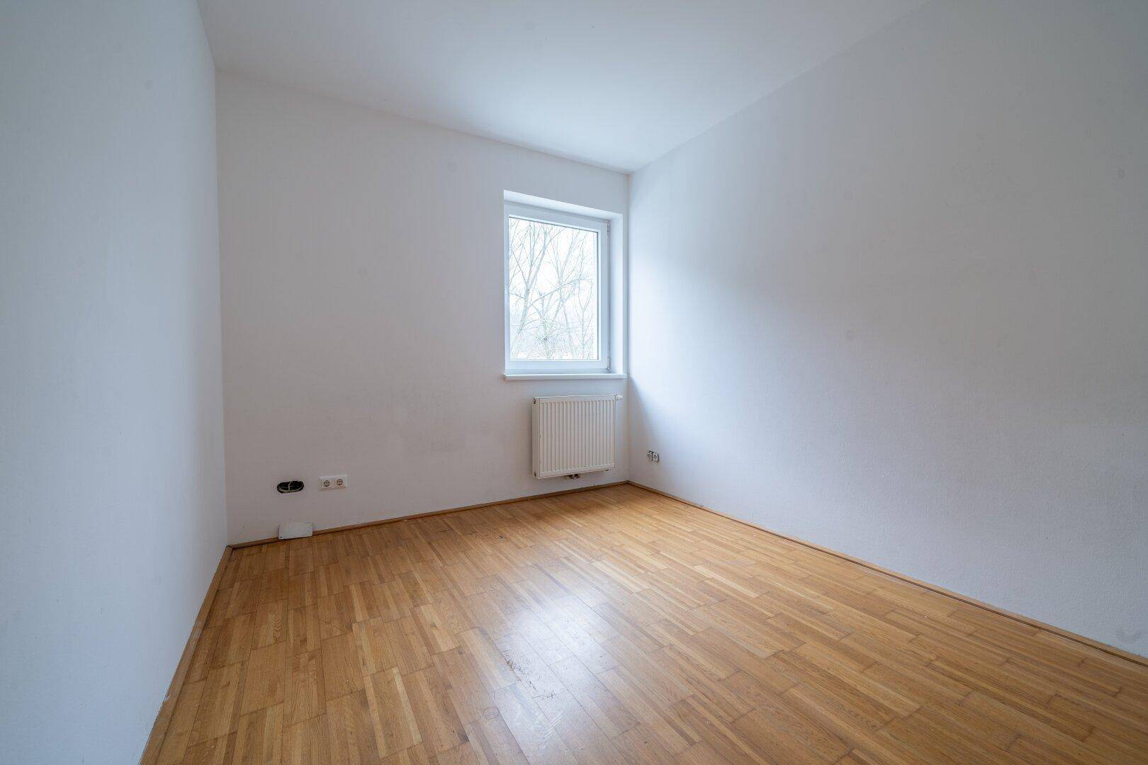 Einfaches Zimmer mit Parkettboden und einem Fenster, ideal für individuelle Wohnbedürfnisse.