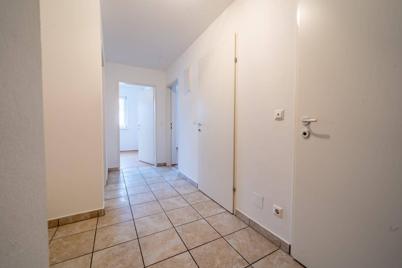 Heller Flur mit beigefarbenen Fliesen und mehreren Türen zu den angrenzenden Räumen.