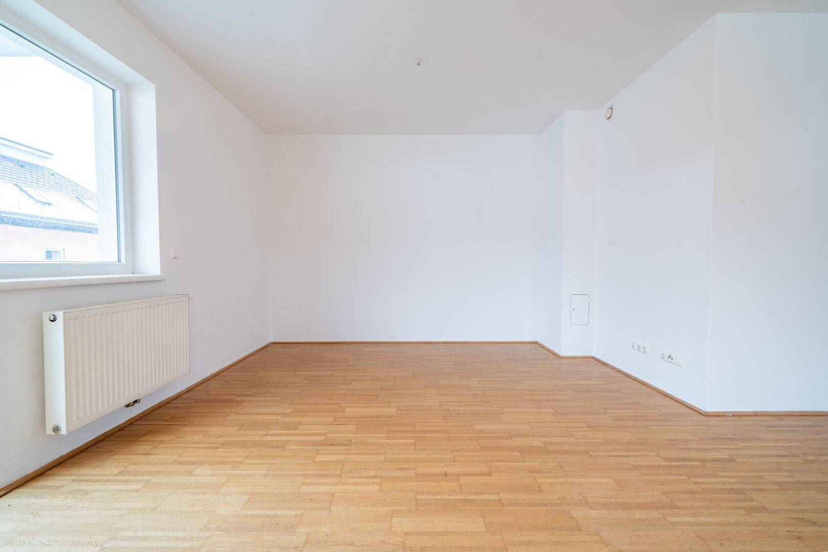 Geräumiges, helles Zimmer mit Parkettboden und weiß gestrichenen Wänden, bereit zum Einzug.
