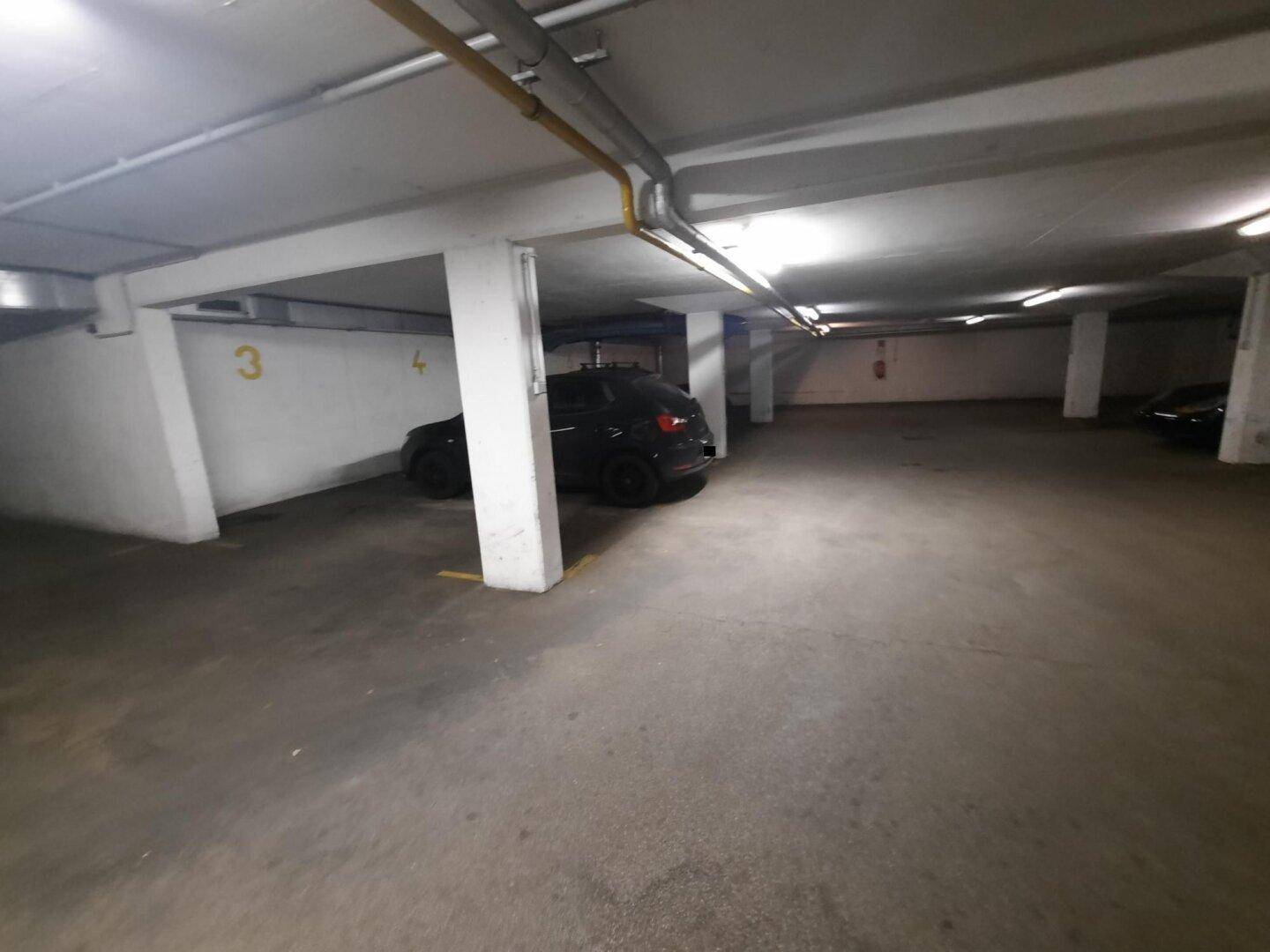 Weitläufige Tiefgarage mit Säulen und nummerierten Stellplätzen, sauber und funktional beleuchtet.