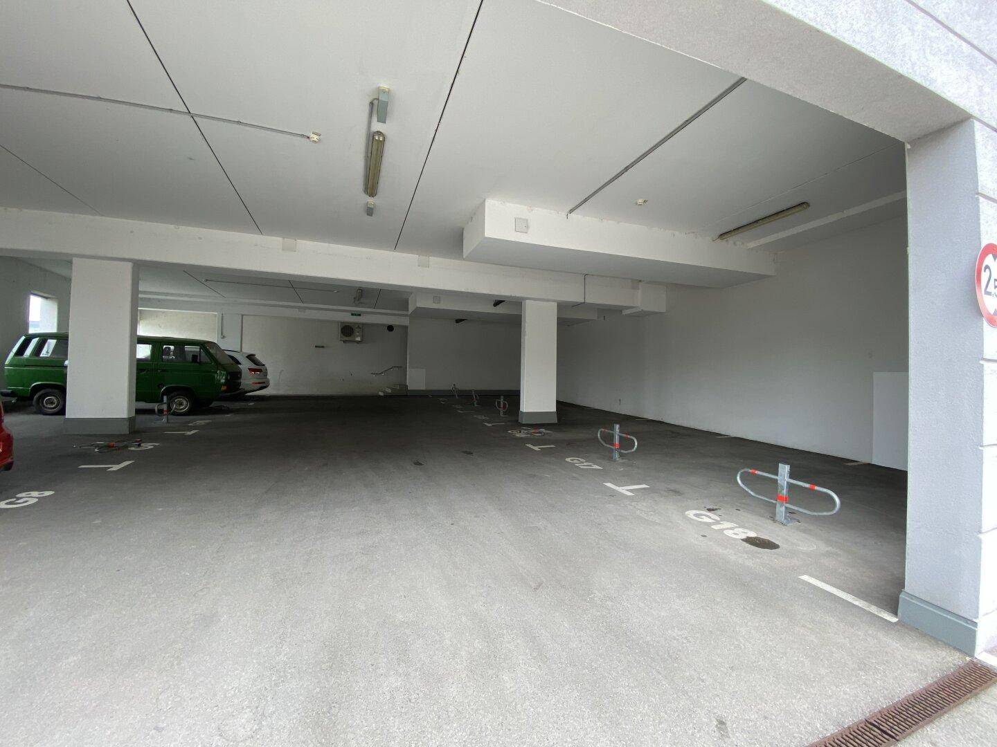 Weitläufige Tiefgarage mit zahlreichen Stellplätzen, einigen Fahrzeugen und guter Beleuchtung.