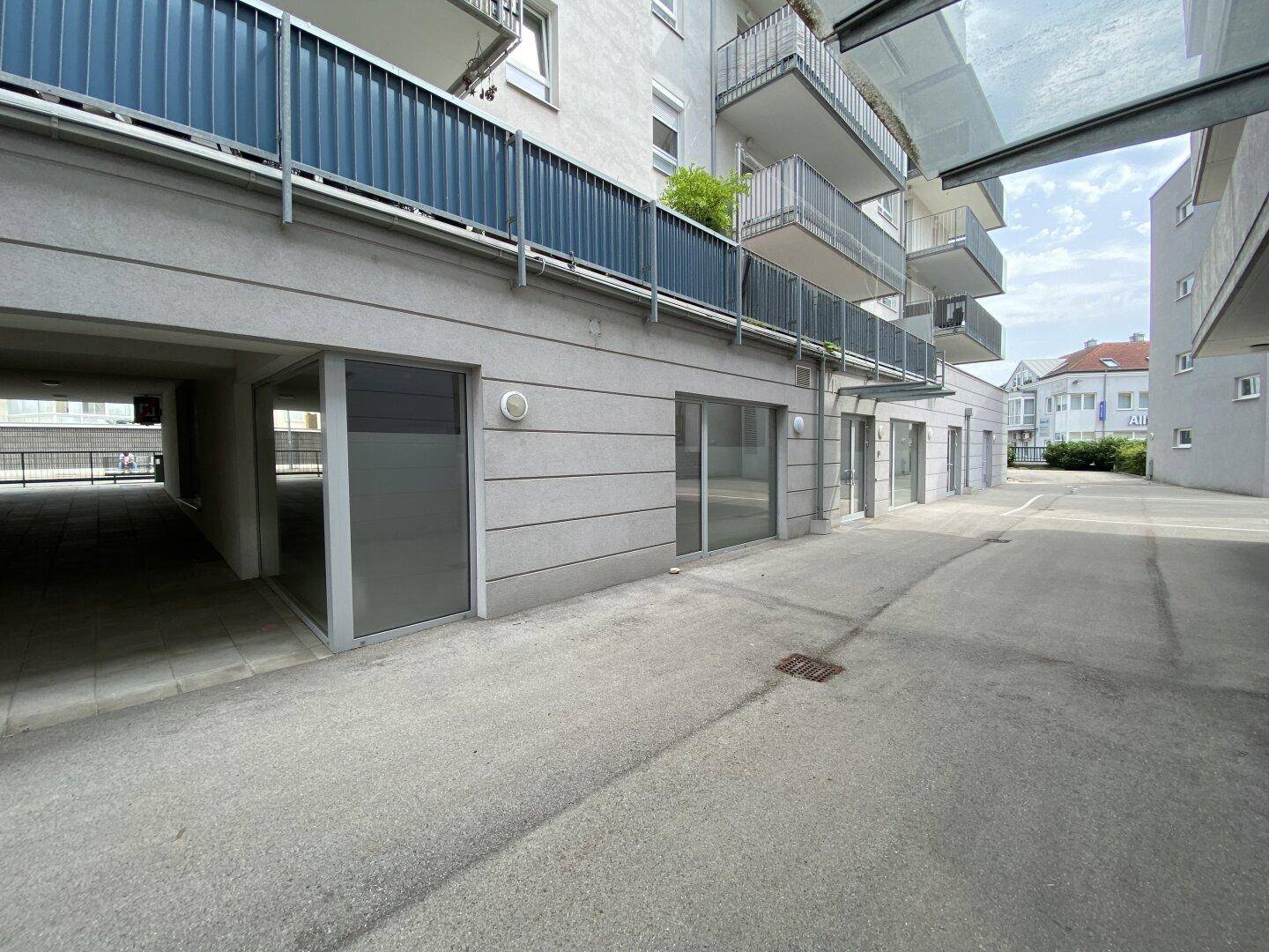 Moderne Gebäudefassade mit Balkonen und dem Eingang zur Tiefgarage, in einer städtischen Umgebung.